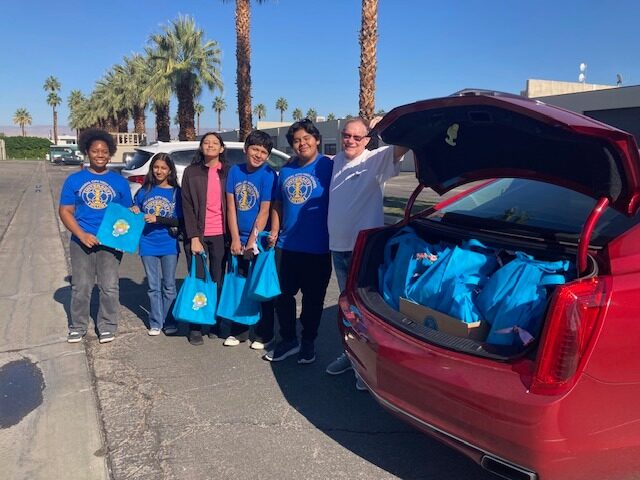 Interact students with a Rotarian delivering bagged meals