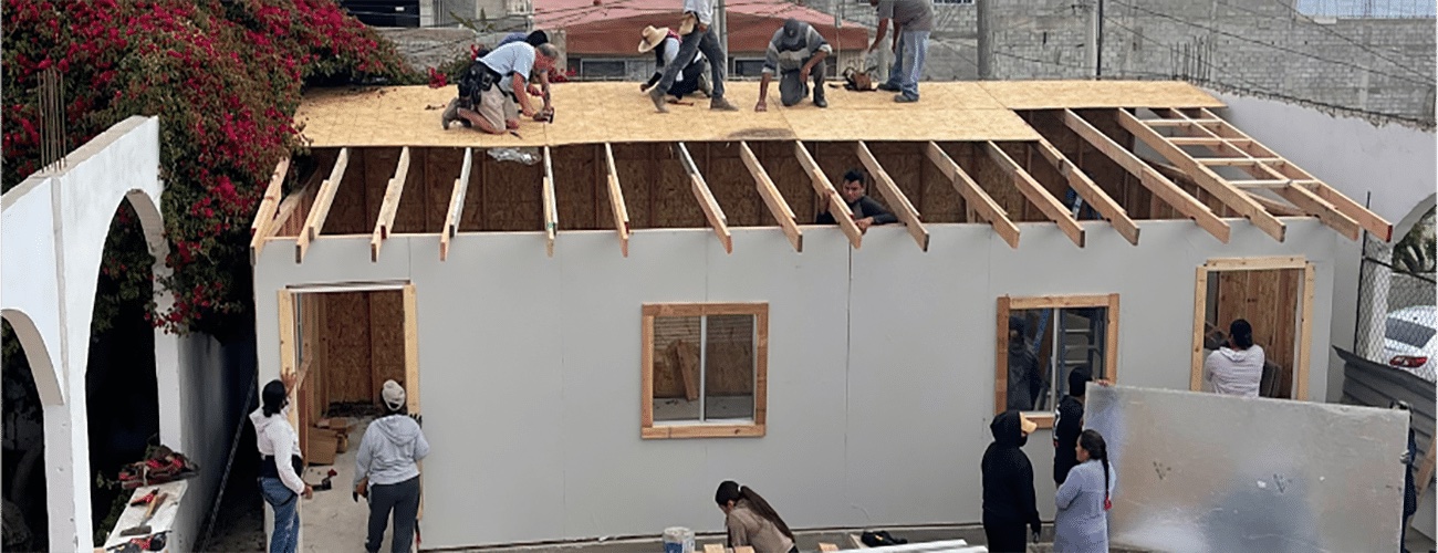 Volunteers raising the frame and roof of a new Coraz&oacute;n home