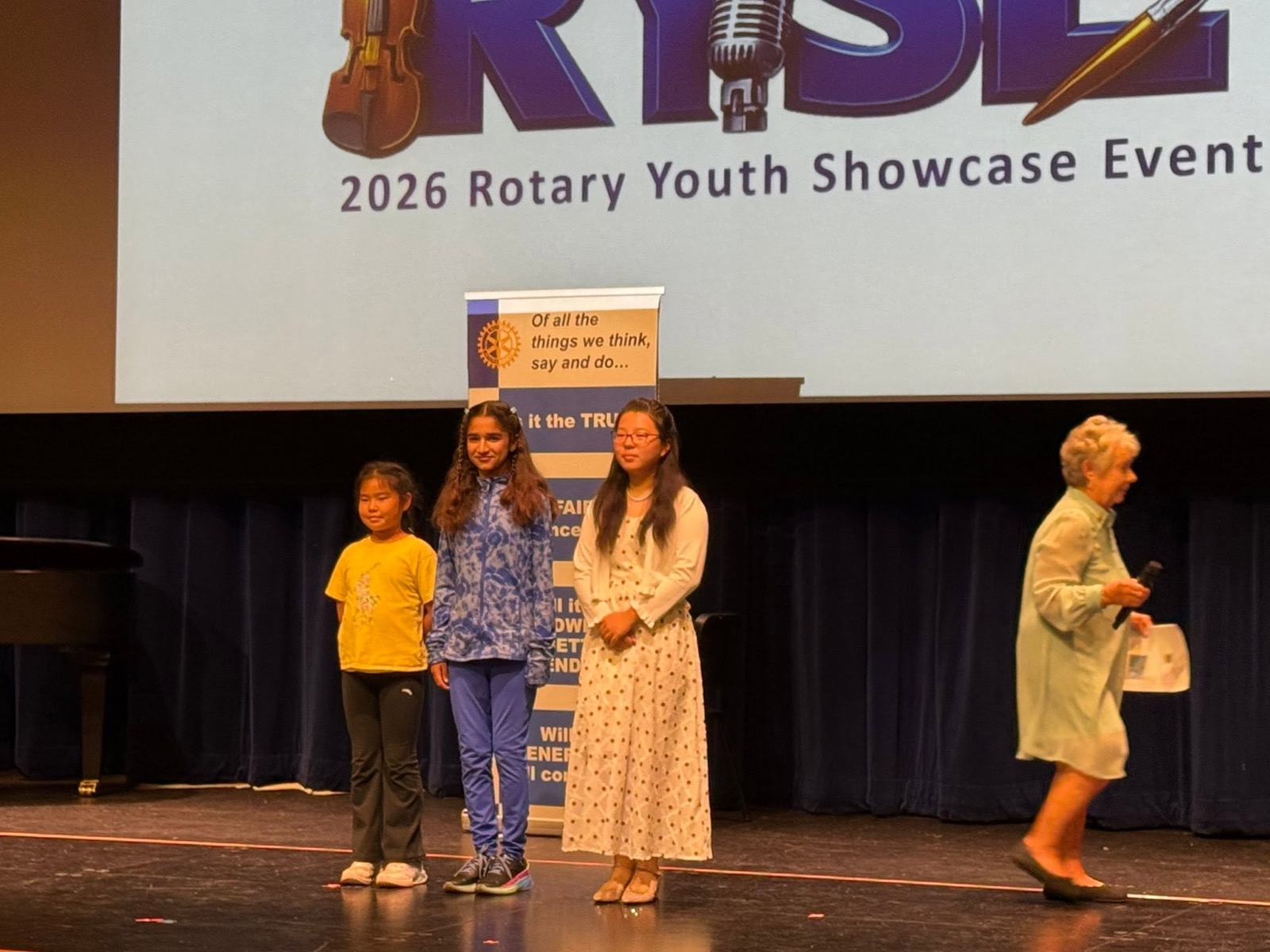 Three young RYSE 2026 finalists recognized on stage beneath the Rotary Youth Showcase Event banner