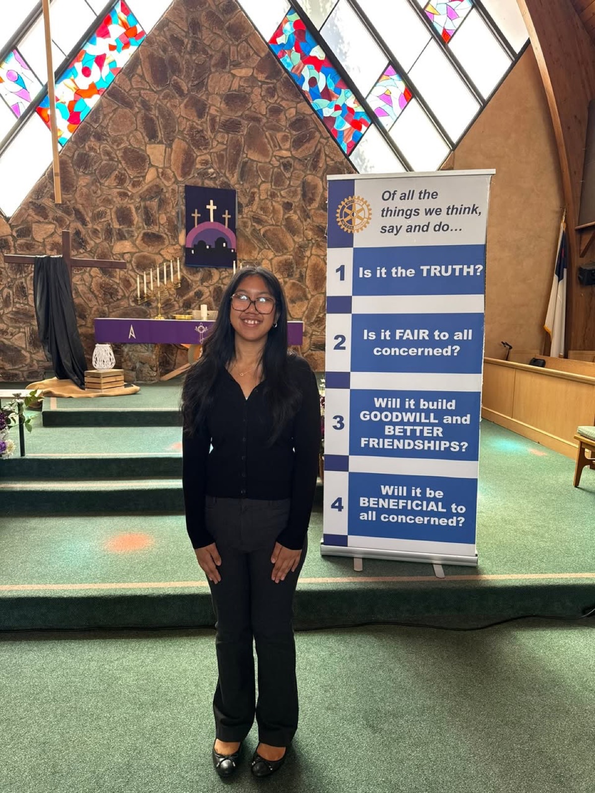 A contestant beside the Four-Way Test banner