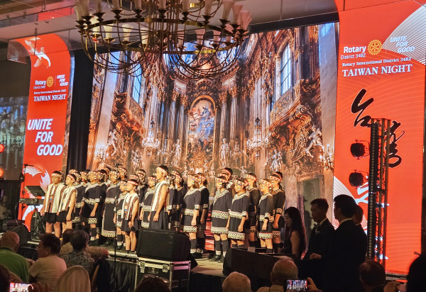A children's choir in traditional Taiwanese dress performing on stage beneath a Taiwan Night banner