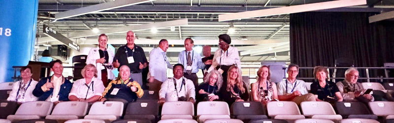 A row of District 5330 Rotarians seated in the Taipei Dome smiling toward the camera during a general session