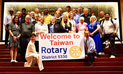 Rotarians from District 5330 gathered on a staircase behind a banner reading Welcome to Taiwan, Rotary District 5330