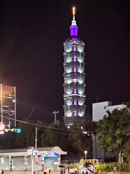 The Taipei 101 skyscraper lit up in white and purple against a night sky