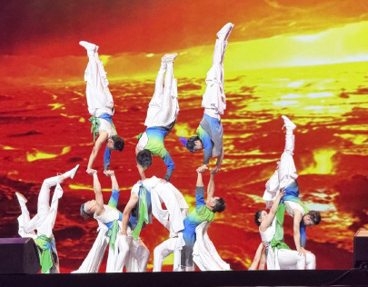 Members of the Taiwan Acrobatic Troupe performing handstands and balances against a red and orange backdrop
