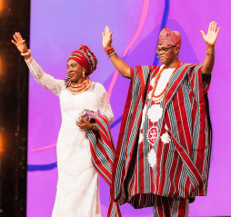 Rotary International President Yinka Babalola and his wife Precy in traditional Nigerian dress, waving from the stage